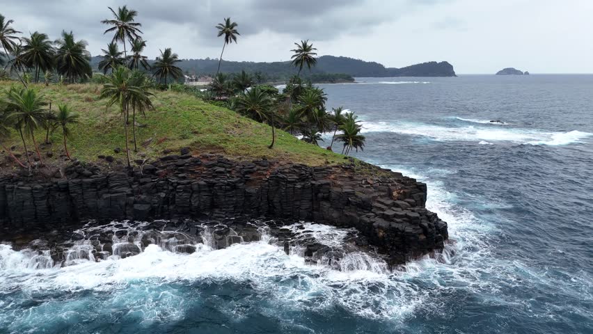 aerial drone view of verdant peninsula jutting into the Atlantic Ocean, featuring dark cliffs and lush green grass.