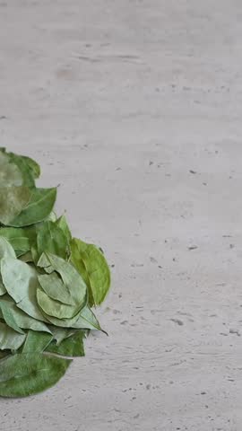 Person placing a small bowl of coca candies next to a pile of dried coca leaves. This traditional andean remedy helps with altitude sickness