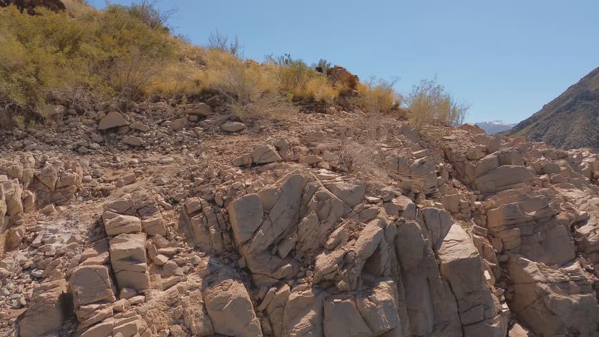 Aerial fly by of the rocky shoreline of lake Potrerillos in Mendoza, Argentina.