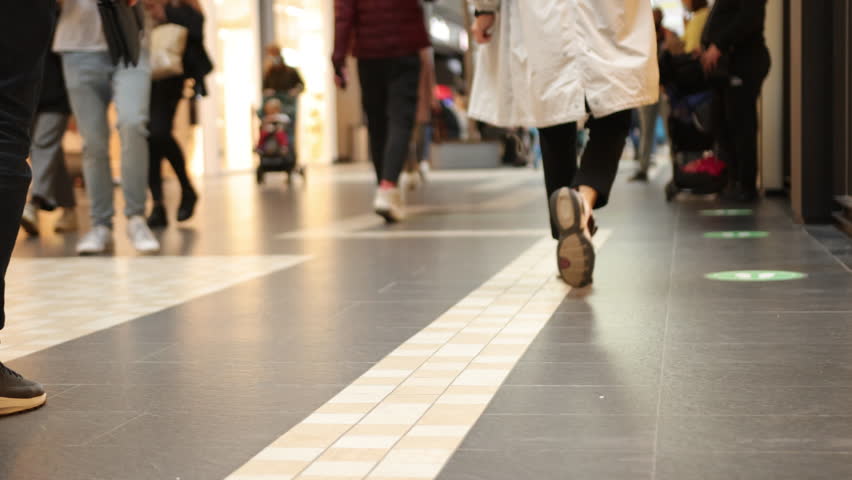 people walking, shopping mall, crowd walking. Crowd of people in mall during shopping time, close up of legs holding shopping bags, selective focus, modern floor and crowd walking along it