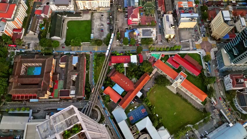 Aerial view of buildings with red roofs and a train on a railway track cutting through the heart of the city, Kuala Lumpur, Federal Territory of Kuala Lumpur, Malaysia.