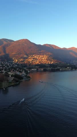 Aerial view of the serene Lake Como and the orange-tinted mountains in the background, creating a captivating contrast of colors, Como, Lombardy, Italy.