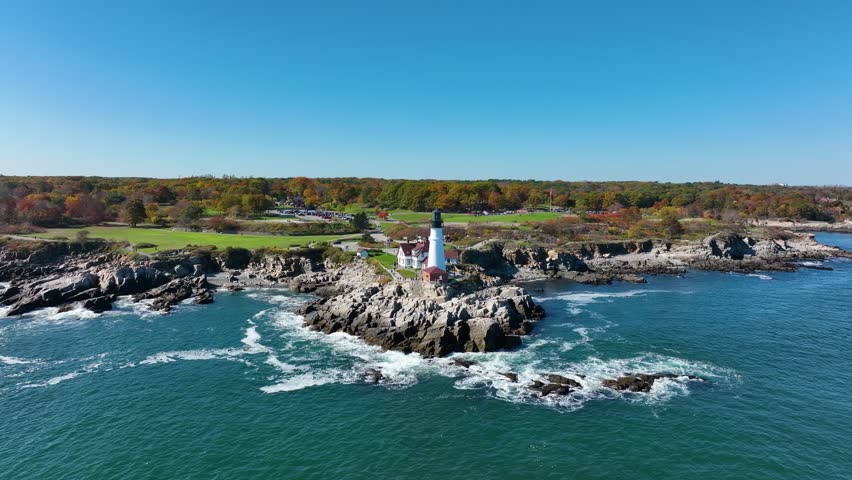 Aerial view of the Cape Elizabeth Lighthouse standing tall on a rocky outcrop where the blue ocean meets the rugged coastline, Cape Elizabeth, Maine, United States.