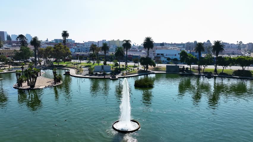 Aerial view of the MacArthur Park fountain, with its shimmering water and lush greenery contrasting against the backdrop of the city, Los Angeles, California, United States.
