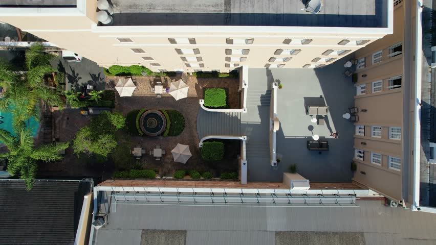 Aerial view of a lush courtyard with a pool, palm trees, and seating areas, contrasting with the surrounding buildings, New Orleans, Louisiana, United States.