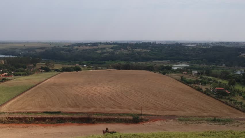 Wide aerial view of prepared farmland field near a river and rural landscape