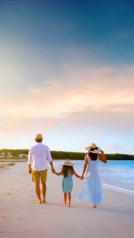 A family on summer holidays walks on a tropical beach during golden sunset time as a concept for travel and vacations with copy space