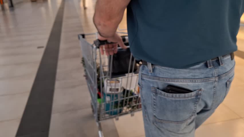 Defocused Man shopping with cart. Retail store interior