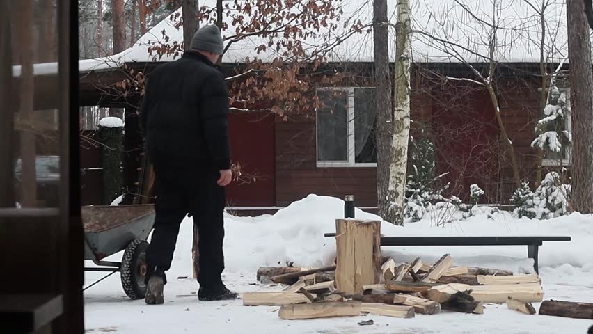 A man chops firewood in the forest near his house