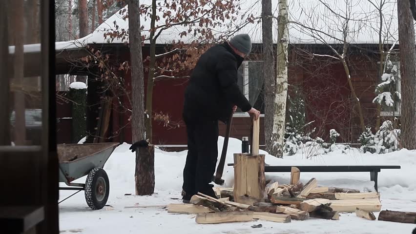 A man chops firewood in the forest near his house