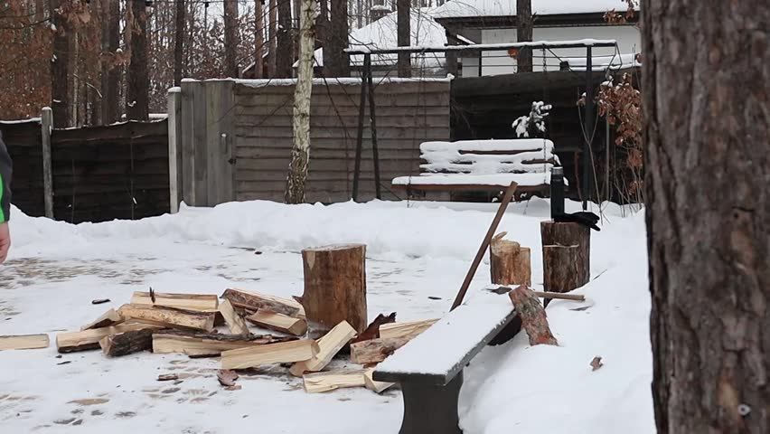 A man chops firewood in the forest near his house