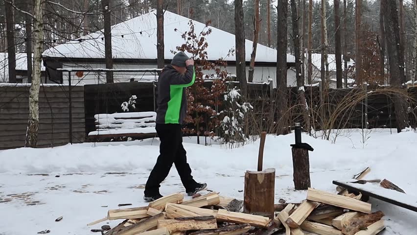 A man chops firewood in the forest near his house