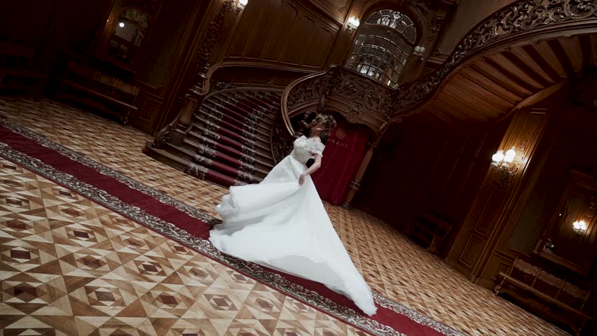 Bride in a grand hall twirls in her wedding dress during a special moment
