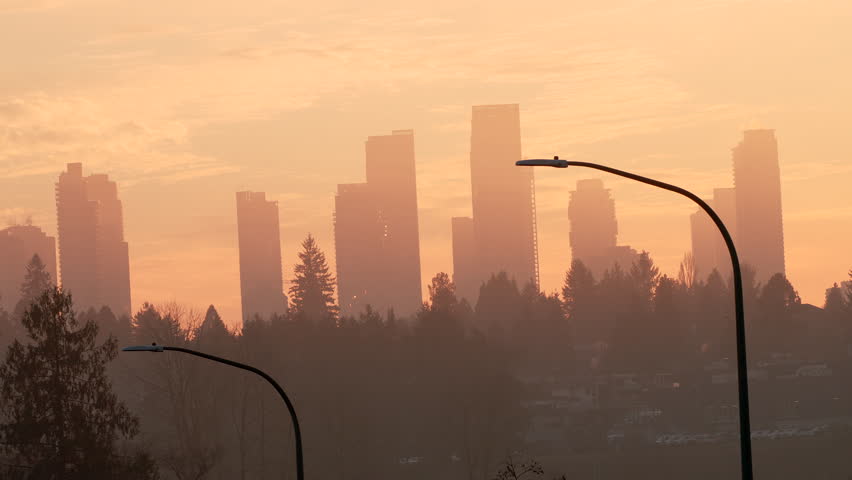 Distant city skyline silhouette at sunset with mist in the air