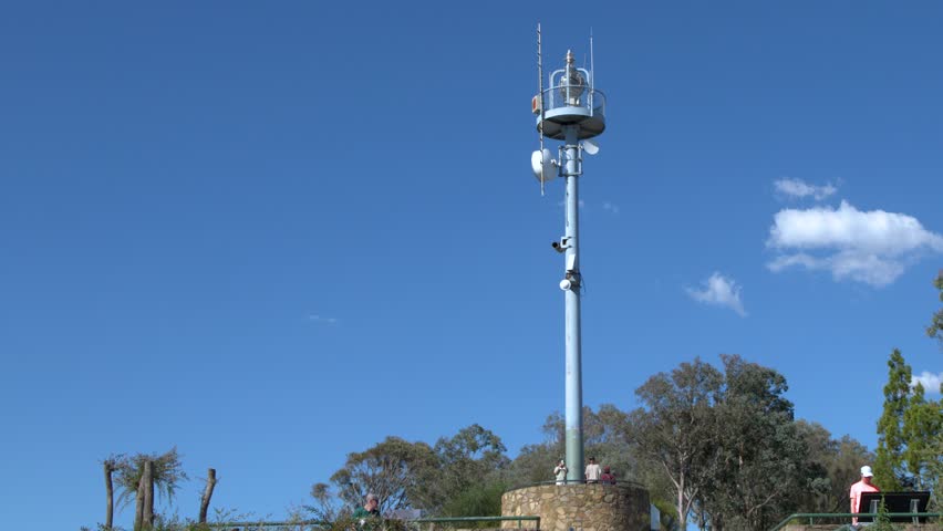 Static wide shot of a metal broadcasting antenna tower under a clear blue sky