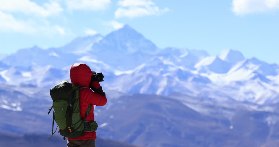 Backpacking woman photographer taking photo with Mount Everest in the background