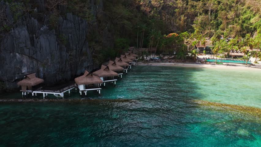 Smooth drone orbit reveals turquoise lagoon and island resort calm mood