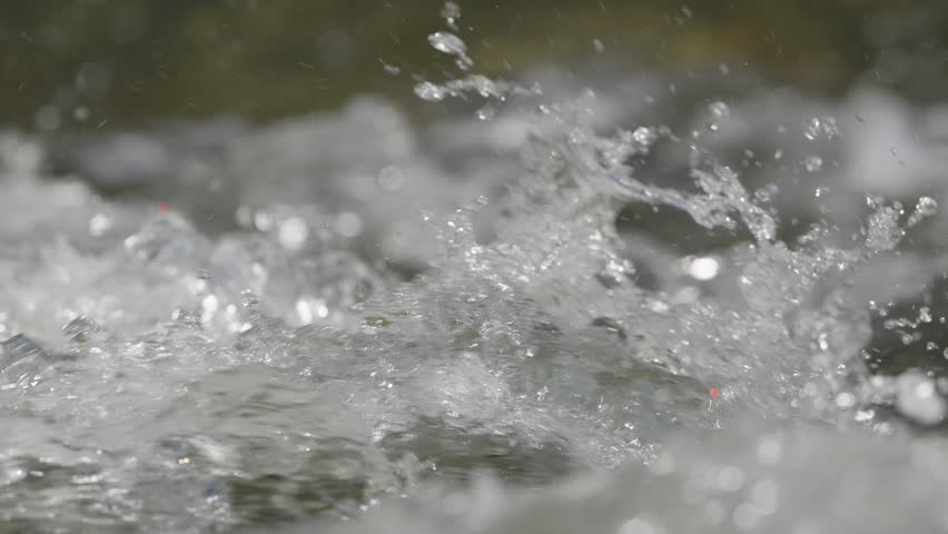Water in a river moving fast in slow motion and macro