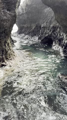 View from inside a dark coral reef sea cave looking out to the turquoise ocean water in Xiaoliuqiu, Taiwan