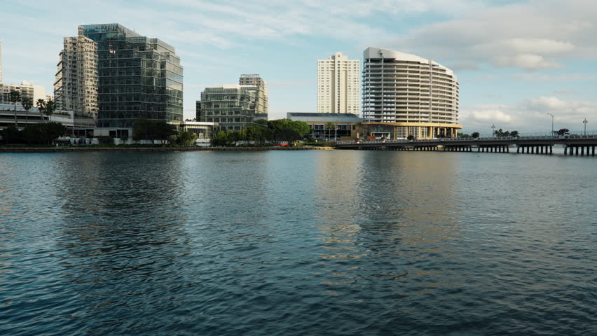 Calm waterfront view of modern residential buildings in downtown Miami, featuring high rise apartments, reflective water surface, coastal atmosphere, and contemporary urban living.