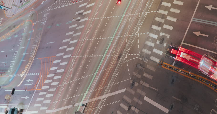 Urban traffic intersection captured at night with vehicles moving through illuminated signals and crosswalks, highlighting the vibrant city atmosphere. Time-lapse, Seoul, South Korea