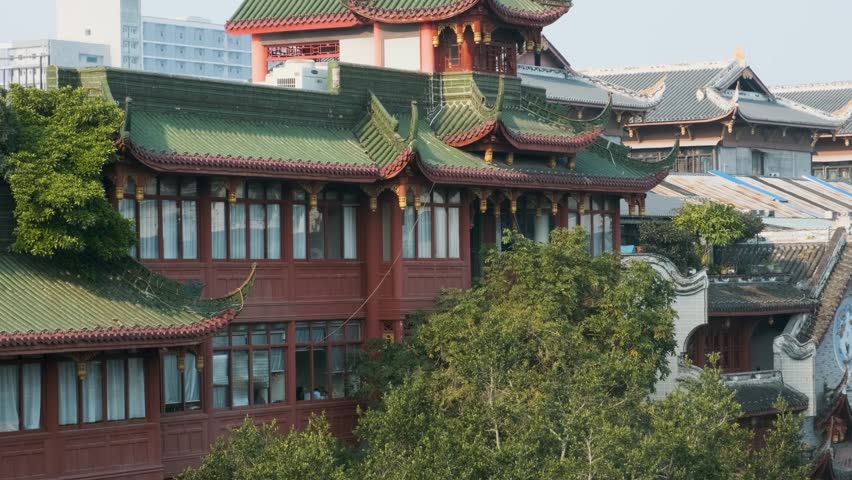 Traditional Chinese building with green tiled roofs and ornate architectural details surrounded by modern cityscape. Chinese temple architecture in Chengdu, China. Travel destination in Asia