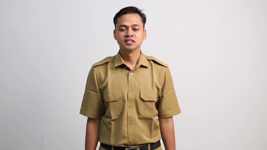 A smiling civil servant man looks at the camera while making a strong gesture while raising his clenched fist.