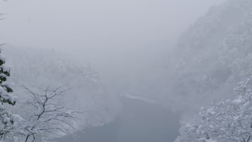 Heavy snow and fog scenery at viewpoint over river with bridge