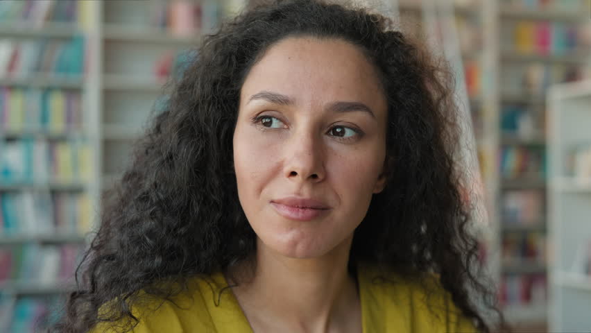 Close up Latina Caucasian Hispanic woman looking at camera in library female girl student studying university high school learning portrait face expression teacher college emotion inside learner focus