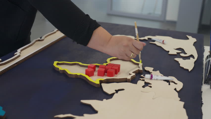 A Participant Carefully Paints Wooden Map Pieces During a Hands-on Painting Class - Close Up