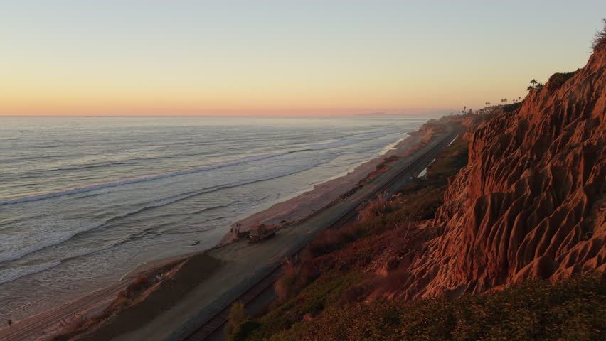 Sandstone Cliffs in Del Mar, California at sunset. People enjoy a walk on the beach. Slow zoom in shot.