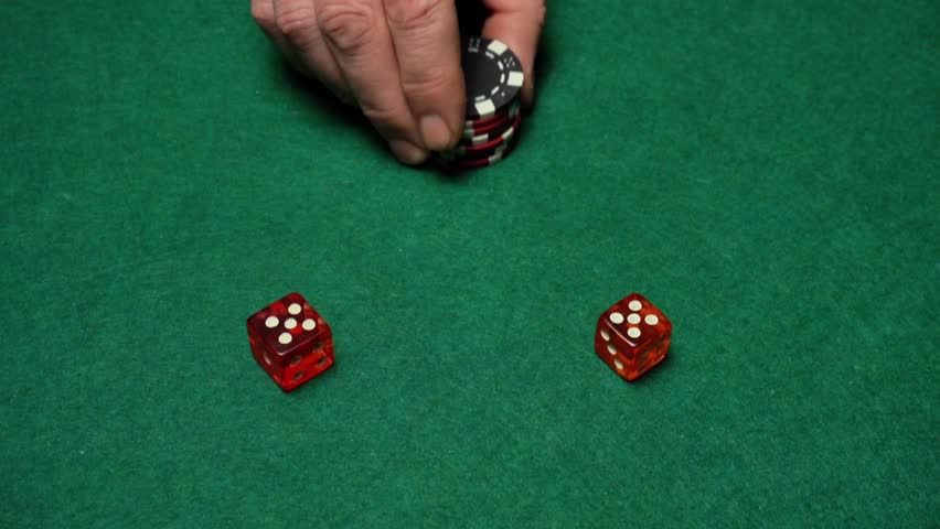 Hand positions a stack of poker chips beside two red dice on a green felt table, capturing the essence of a gaming scenario in a casino setting with vibrant colors and clear details