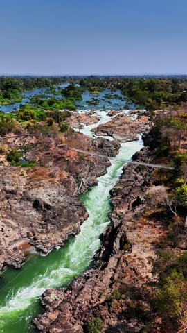 Drone hovering over Don Det Island, Mekong river with turquoise waters, brown rocks and the bridge, Laos