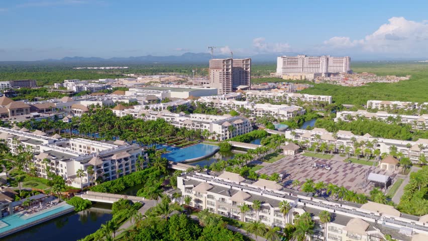 New hotel and resort development in Punta Cana, Dominican Republic, showing modern buildings under construction surrounded by lush greenery in growing tourism destination. Aerial wide shot.