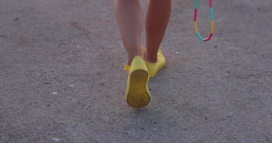 Fit young woman jumping rope at the beach against sea and sky background. Summer sport and healthy lifestyle concept. Slow motion