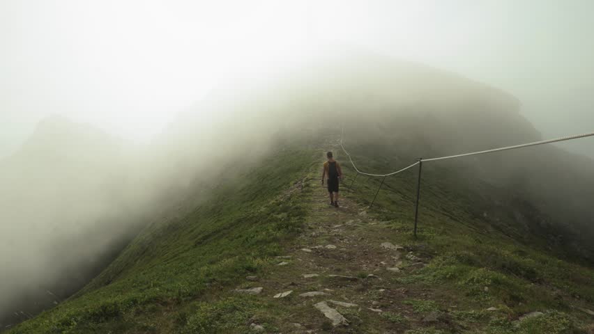 Hiker Hiking To The Peak Of Nyken Mountain On A Foggy Day In Oksnes, Nordland, Norway. - wide shot