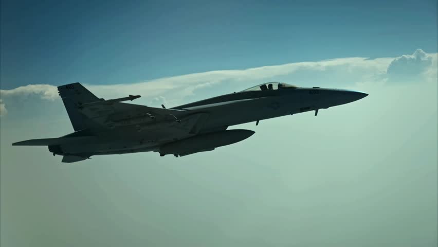 An FA-18 Hornet fighter jet flying through the clouds during a training mission.