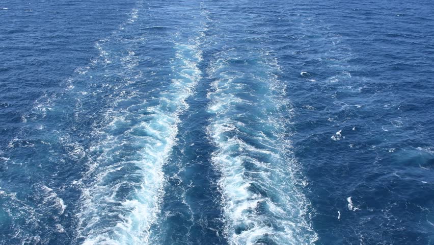 Abstract view of rapid water movement and foamy sea wake in the sunlight 