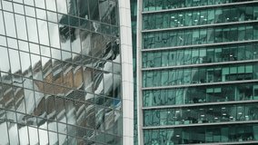 Close-up of adjacent modern glass skyscraper facades, showing reflective windows, office interiors, distorted reflections, and teal-tinted curtain wall geometry in an urban skyline - Powered by Shutterstock - Get 15% off with code: PIKWIZARD15