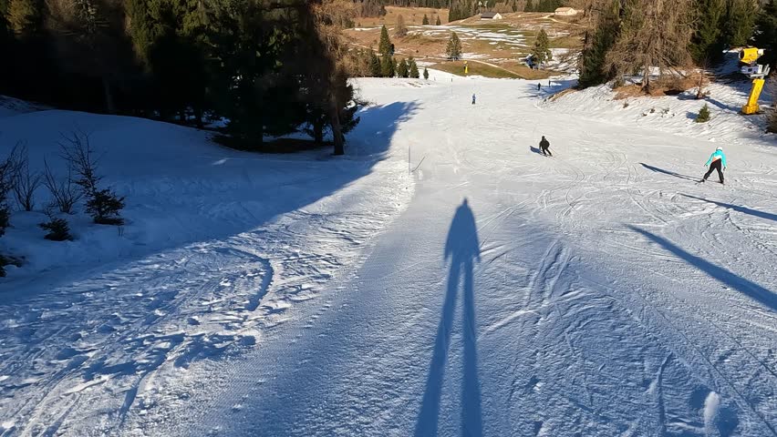 POV shadow of skier gliding on groomed snow piste with corduroy texture in Folgaria Italy sunny afternoon winter sport perspective