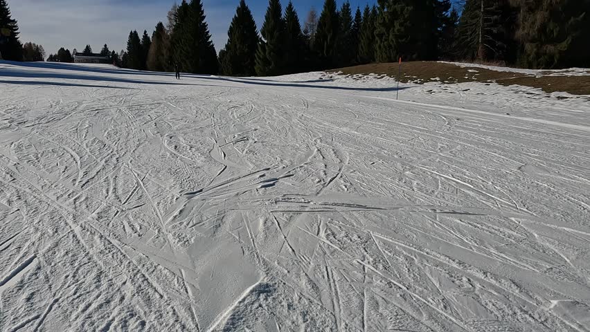 Lone Skier on Horizon of Snowy Mountain Slope in Folgaria. Silhouette against Bright Sun and Blue Sky. Winter Sport Concept in Italian Alps.