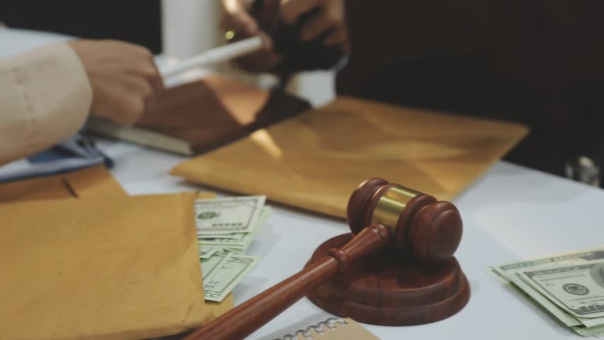 Judge gavel with Justice lawyers having team meeting at law firm in background. Notary with client in office