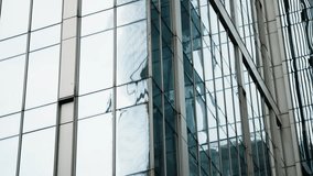 Reflective glass facade of a modern skyscraper showing distorted reflections of neighboring towers, grid-like window patterns, and sleek urban geometry across the skyline - Powered by Shutterstock - Get 15% off with code: PIKWIZARD15