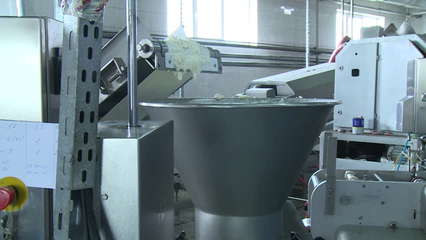 White, creamy dairy product processed by industrial machinery on a conveyor belt in a modern food factory. Automated production of fresh cheese curds.