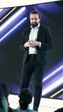 Vertical Video Male CEO presenting new mobile phone product launch on stage with premiere of modern smartphone interface. Entrepreneur introduces innovation and development with product release - Powered by Shutterstock - Get 15% off with code: PIKWIZARD15