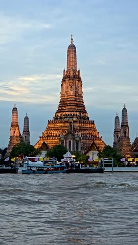 Experience the breathtaking beauty of Wat Arun as the sun sets over Bangkok Thailand. The temple ornate design glows brightly against the vibrant sky, creating a magical atmosphere along the river.