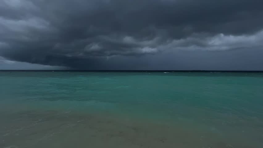 Cinematic dark sky over the Indian Ocean in the Maldives, Ukulhas Island, cloudy day, dark clouds over turquoise water, sandy beach in bad weather