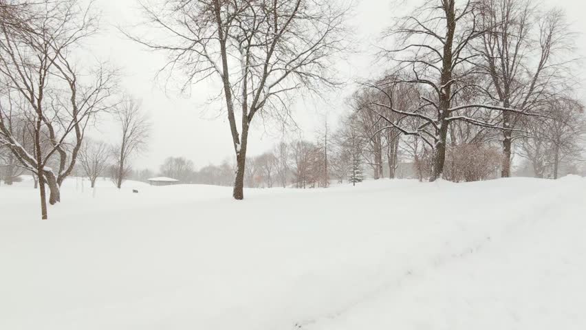 First person view walking along snowy park path during winter.
