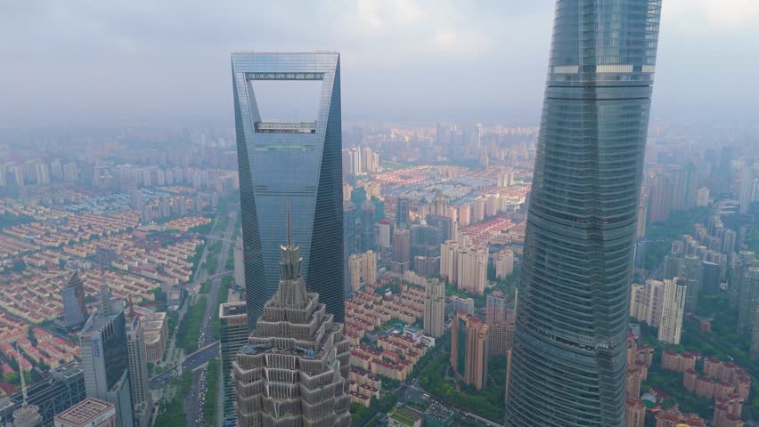 Aerial shot of the Shanghai Tower, SWFC, and Jin Mao Tower, surrounded by dense high-rise residential and commercial architecture in the Pudong financial district, Shanghai, China.