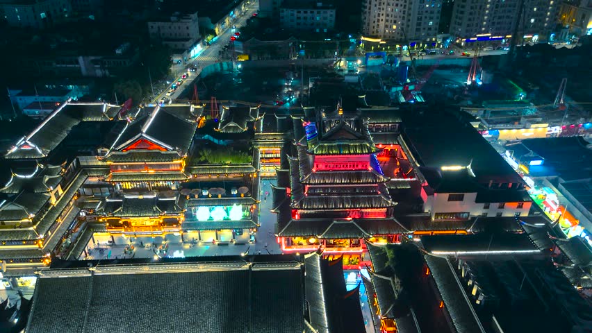 Aerial perspective of traditional Chinese architecture and large crowds walking through the illuminated Yu Garden at night, Shanghai, China.